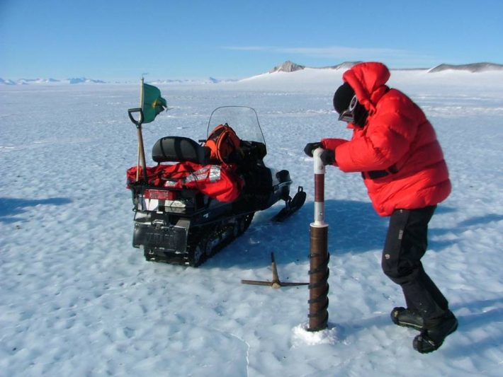 Pesquisador perfura o gelo para coleta de um testumunho (amostra cilíndrica), em uma expedição anterior na Antártida. Foto: UFRGS/INCT da Criosfera
