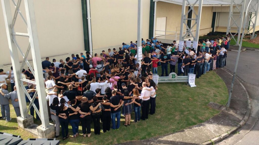 Funcionários da fábrica de vacina da influenza dão abraço simbólico na fábrica. Foto: Divulgação/via Estadão